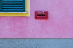 Boite postale rouge, sur mur rose, cadre de fenêtre jaune, vole