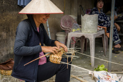 Artisanne tressant un panier avec des pailles de riz au marché